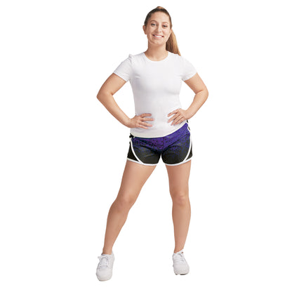 Model wearing S‑Line paneled performance shorts in black with white piping trim and purple geometric panel, mid-rise fit with elastic waistband—styled for dance, drill, or color guard
