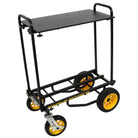Black carpeted laptop/media shelf installed on a Rock N Roller R8/R10/R12 cart, showing two-tier setup with 32–50″ foldable platform supported by steel poles and mounted between upright handles